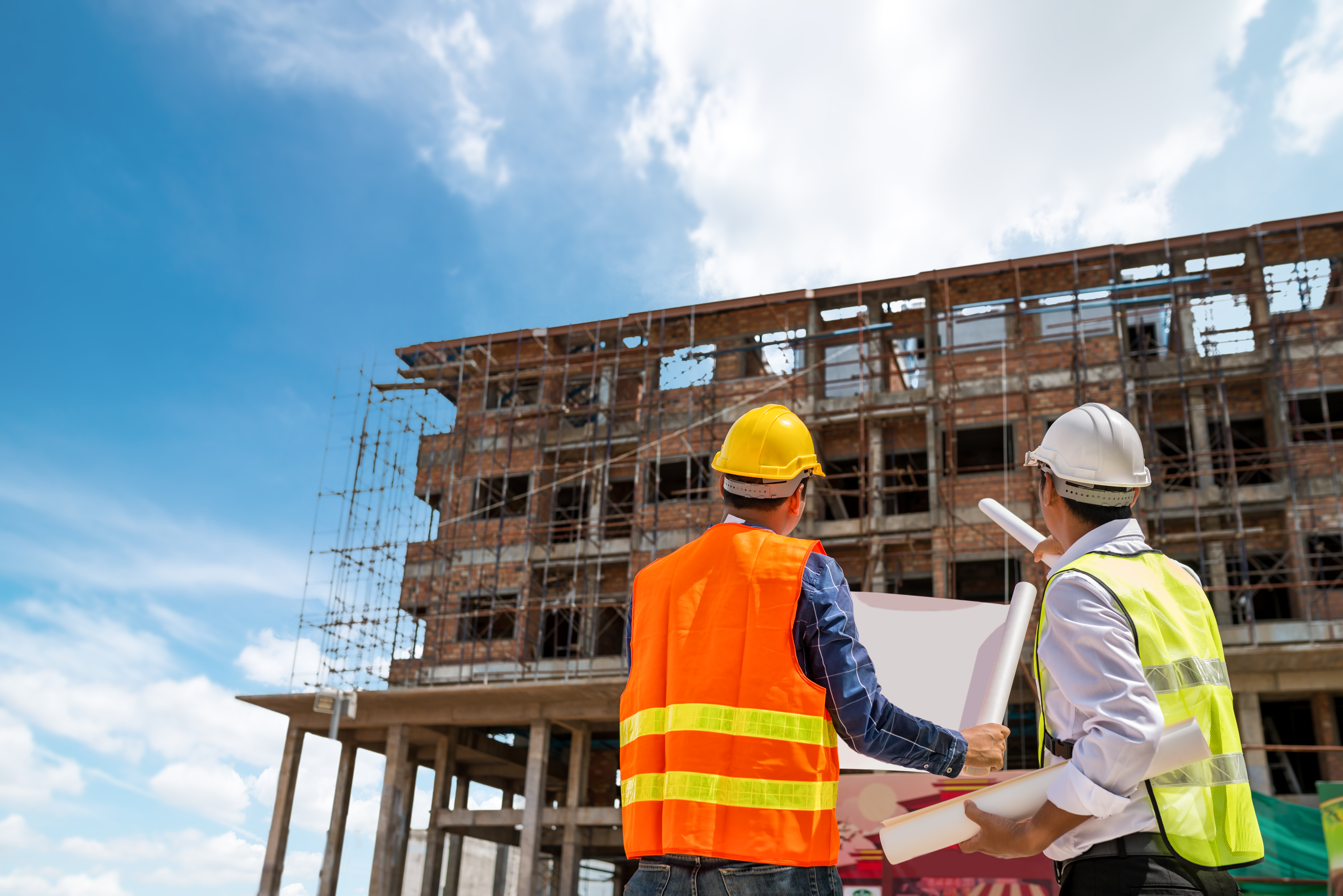 Construction site with two workers in safety gear looking at building
